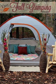 a tent that is in the woods with pillows on it and two chairs next to it