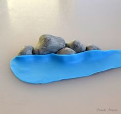 three rocks sitting on top of a blue piece of plastic that is floating in the water