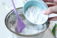 a person holding a spoon in a cup filled with white powder