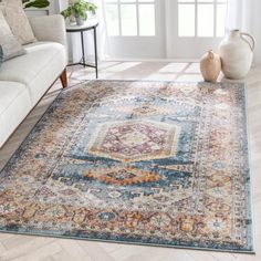 a blue and yellow area rug with an ornate medallion design on the center in front of a white couch