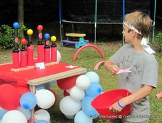 a young boy standing next to a table with balloons on it