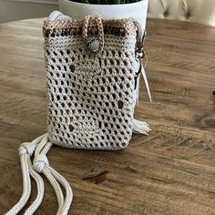 a crocheted bag sitting on top of a wooden table next to a potted plant