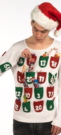 a woman wearing a christmas sweater with candy bars on it and santa's hat