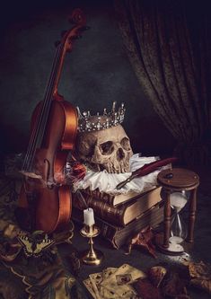 a skull wearing a crown sitting on top of a table next to a book and a violin