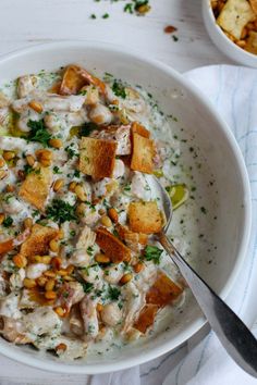 a white bowl filled with food next to a spoon