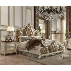 a fancy bedroom with chandelier, bed and dressers in white and gold