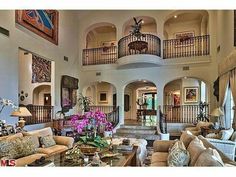 a living room filled with lots of furniture next to a staircase leading up to a second story