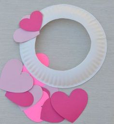 a paper plate with pink and red hearts on it next to a circle of cut out heart shapes