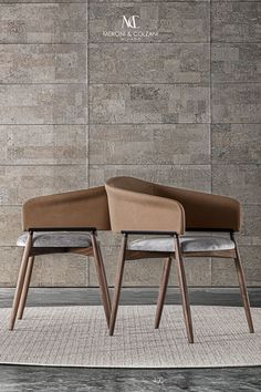 two chairs sitting on top of a rug in front of a wall with a brick pattern