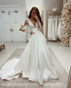 a woman taking a selfie while wearing a wedding dress in front of a mirror