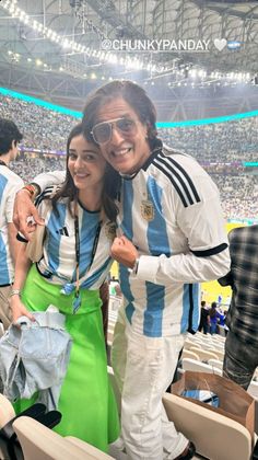 a man and woman standing next to each other at a soccer game in the stadium