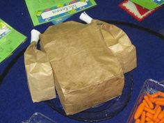 a brown paper bag sitting on top of a table next to carrots and broccoli