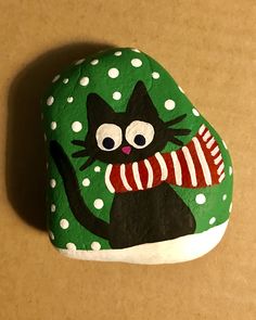 a painted rock with a black cat on it