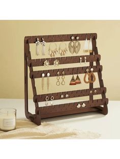 a wooden jewelry rack with earrings on it and a candle next to the display case