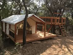 a small house in the woods with a swing set and treehouse attached to it