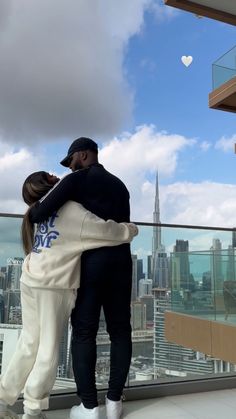 a man and woman embracing each other in front of a cityscape with skyscrapers