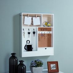 there is a white cabinet with keys and other items on it next to a potted plant