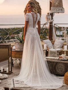 a woman in a wedding dress is standing on a deck with her back to the camera