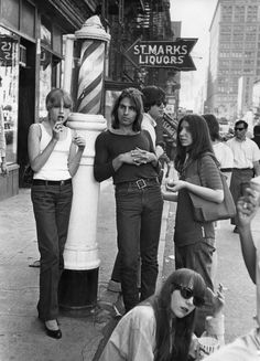 several women standing on the sidewalk in front of stores and talking on their cell phones