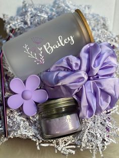 a jar filled with lavender colored powder next to a purple flower