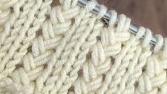 a close up view of the crochet stitchs on a white knitted blanket