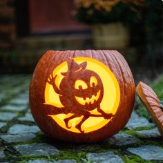 a carved pumpkin with an evil face on it's side, sitting on the ground