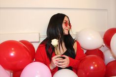 a woman holding a rose in her hands surrounded by balloons