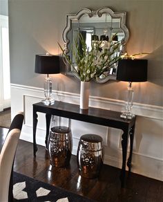 a table with two lamps and a mirror on it in the middle of a room