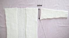 the crocheted sweater is being sewn and stitched with white yarns