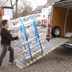 a man is unloading a ladder from the back of a moving van with its door open