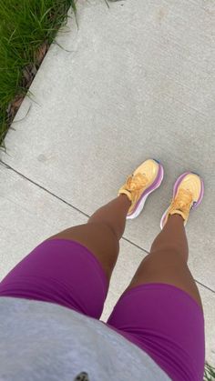 the legs of a woman in purple shorts and yellow shoes are seen from up close