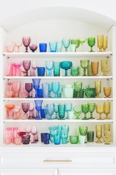 a shelf filled with lots of different colored glasses