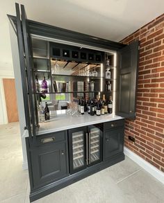 a bar with wine bottles and glasses on it next to a brick wall in a room