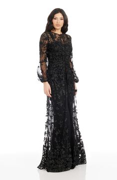 a woman in a long black dress with sheer sleeves and an intricate lace pattern on it