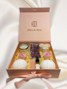 an open box containing candles, soaps and other items on a white cloth background