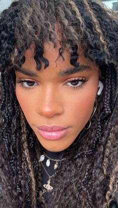 a close up of a person with long curly hair and wearing earrings on her head