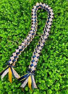 two ribbons are laying on top of some green plants and grass, one is blue and the other is yellow