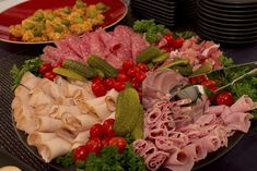 an assortment of meats and vegetables on a platter with utensils in the foreground