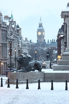 a statue of a lion in the middle of a snowy street with big ben in the background