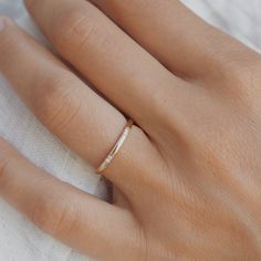 a woman's hand with a gold ring on top of her finger and white cloth