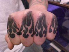 a hand with black ink on it and some flames coming out of the middle finger