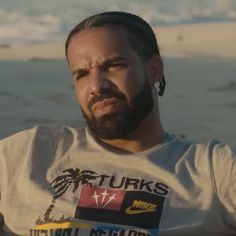 a man with dreadlocks standing in front of the ocean