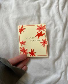 a hand holding a piece of paper with red flowers on it that says, c ambiza pomegranate