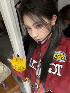 a girl with long black hair wearing a red jacket and yellow rubber gloves holding a banana