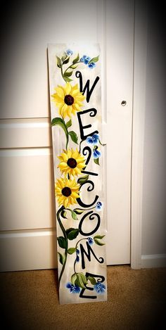 a welcome sign with sunflowers painted on it