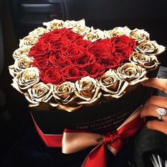 a heart shaped box filled with roses on top of a car dash board next to a woman's hand