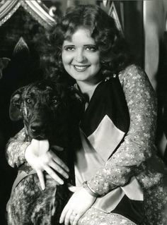 a black and white photo of a woman holding a dog