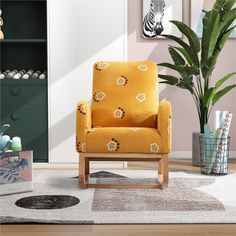 a yellow chair sitting on top of a wooden floor next to a potted plant