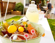 a bucket filled with drinks sitting on top of a table next to a bottle of lemonade