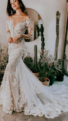 a woman standing in front of a mirror wearing an off the shoulder white wedding dress